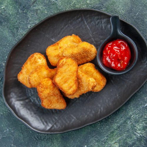 deliciosos-nuggets-pollo-salsa-tomate-placas-negras-sobre-superficie-oscura-espacio-libre-primer-plano